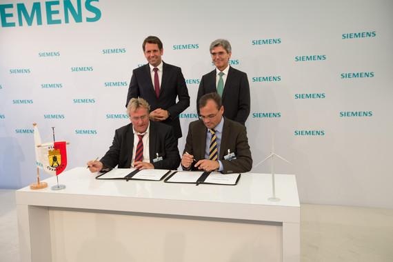 Siemens Cuxhaven | August 2015: Unterzeichnung der Ansiedlungsvereinbarung für eine Fertigung von Windenergieanlagen durch Siemens in Cuxhaven. Siemens-Windenergie-CEO Markus Tacke (sitzend rechts) und Cuxhavens Bürgermeister Ulrich Getsch signieren die Vereinbarung. Hinter ihnen repräsentieren der Siemens-Konzernchef Joe Kaeser (rechts) und Niedersachsens Wirtschaftsminister Olaf Lies (links) größere strategische Interessen. - © Siemens