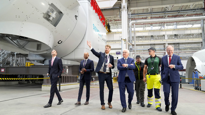 © Siemens Energy Politikerbesuch 2024 vor Maschinenhäusern der SG 14-222/236 DD: Offshore-Anlagen-Fertigung im Werk Cuxhaven bei Siemens Energy mit Bundespräsident Frank-Walter Steinmeier (Mitte), Niedersachsens Ministerpräsident Stephan Weil (rechts) und Werksleiter Kristoffer Mordhorst (3. von links) sowie Werksmitarbeitern