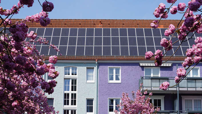 © Carl & Karl - stock.adobe.com Energetisch renoviertes Wohnhaus mit Solarenergie im Frühjahr zur Kirschblüte