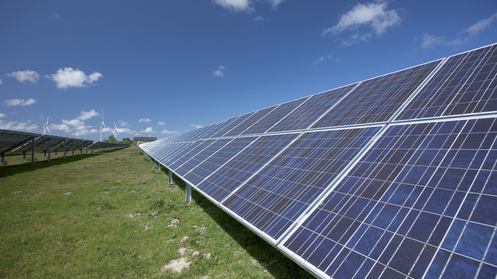 Reihen von Solarmodulen auf einem grasbewachsenen Feld unter einem klaren blauen Himmel mit ein paar Wolken. - © Sharp